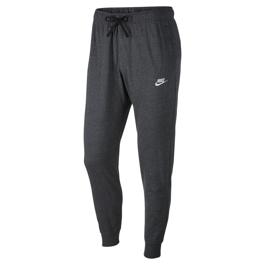 The Nike Club Joggers are dark gray pants featuring an elastic waistband with a drawstring, showcasing the white Nike logo on the left thigh. They come with tapered legs and ribbed cuffs for a snug fit.